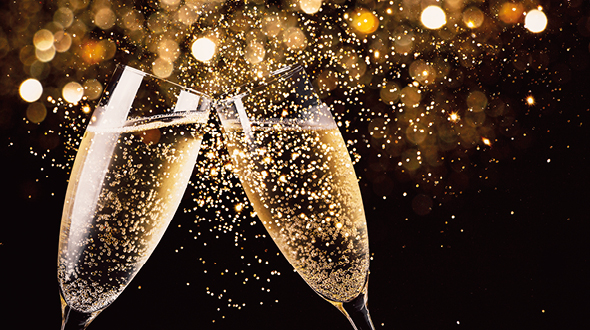 Two champagne flutes clink together, creating a spray of bubbles. The background is filled with soft, golden lights, evoking a celebratory atmosphere. The image symbolizes joy and togetherness, often associated with special occasions or celebrations.