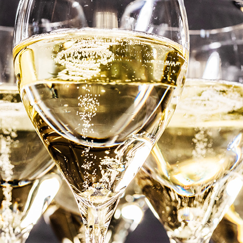 A close-up of several sparkling champagne glasses filled with bubbly, golden liquid. The bubbles rise in the glasses, creating a festive and celebratory atmosphere. The background is softly blurred, emphasizing the clarity and brightness of the champagne.
