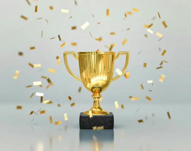 A shiny gold trophy stands on a black base, surrounded by shimmering gold confetti. The trophy symbolizes victory and achievement.