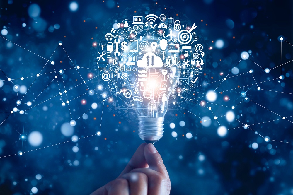 A hand holds a lightbulb from which various icons representing technology, innovation, and digital communication emerge. The background features a dark blue gradient with abstract lines and dots, symbolizing connectivity and ideas.