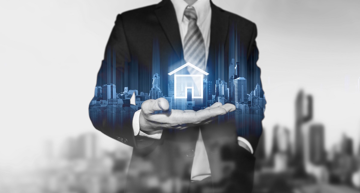 A businessman in a suit holds out his hand, displaying a graphic representation of a house with a city skyline in the background. The image symbolizes real estate and urban development, blending professionalism with a focus on housing.